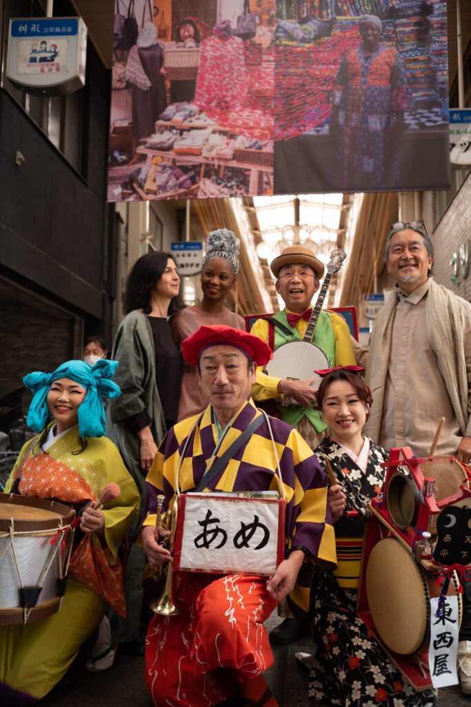 出町桝形商店街で、ちんどん屋さんと一緒に記念撮影のジョアナ・シュマリさん（後列左から2番目）